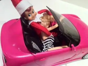 Naughty elf taking Barbie for a car ride